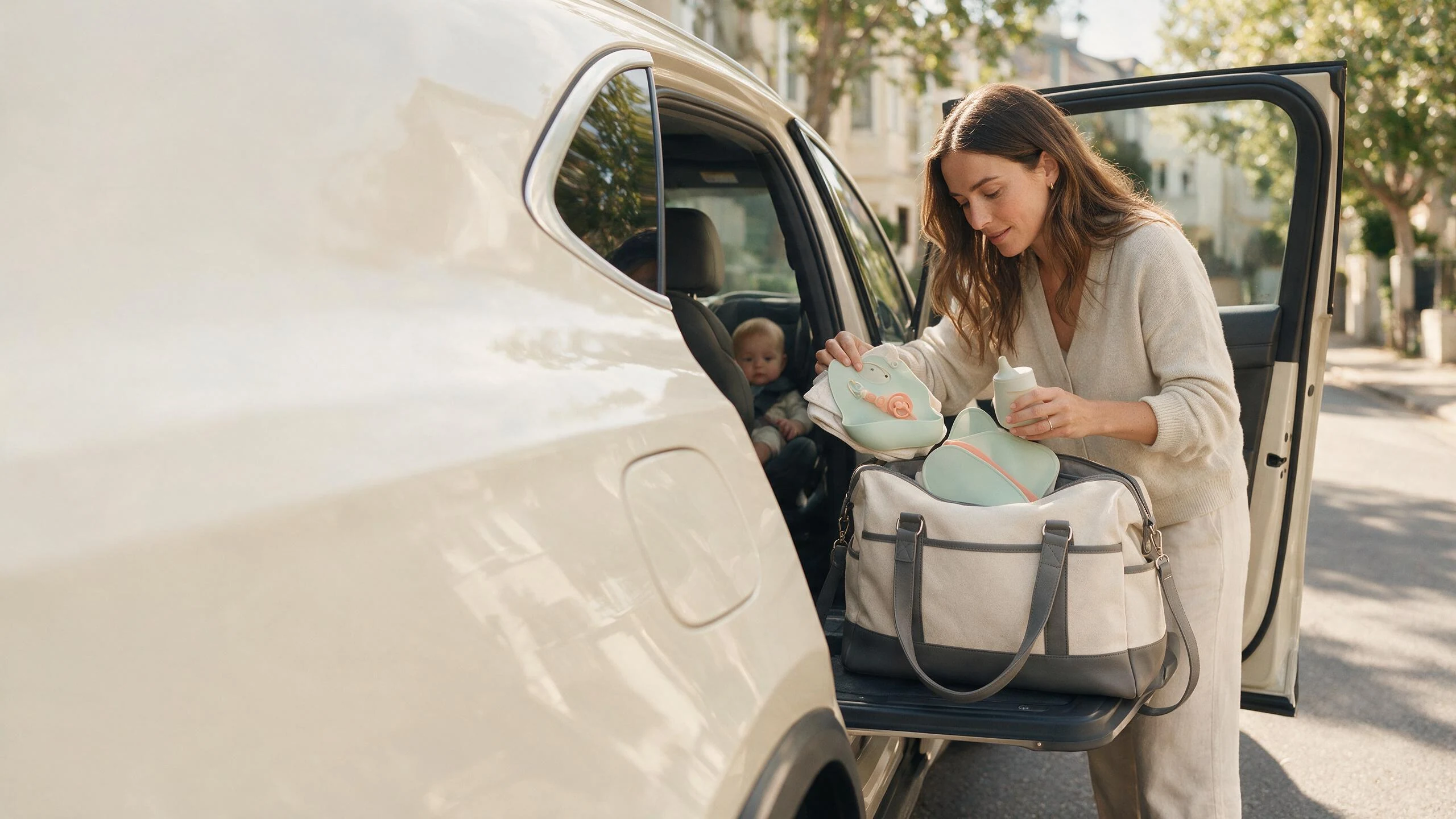 Mother organizing silicone baby essentials beside an open family car door